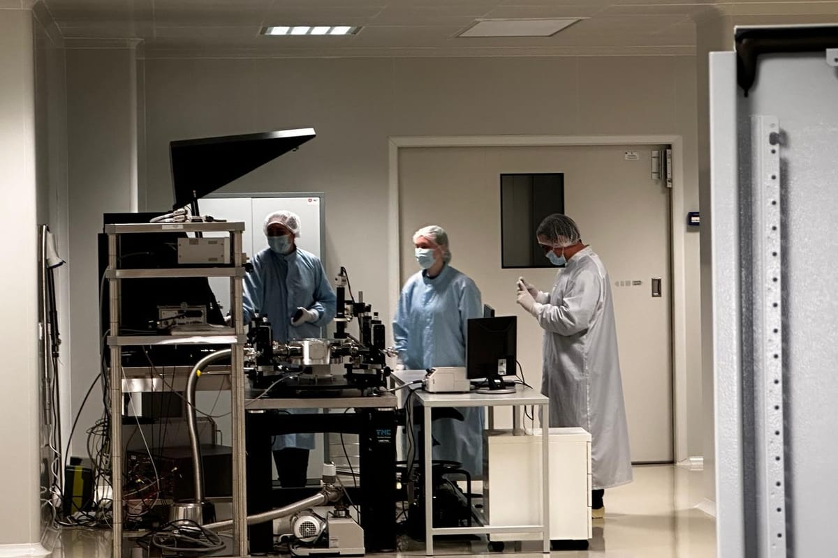 A wider view of the laboratory, with three people working around the probe station.